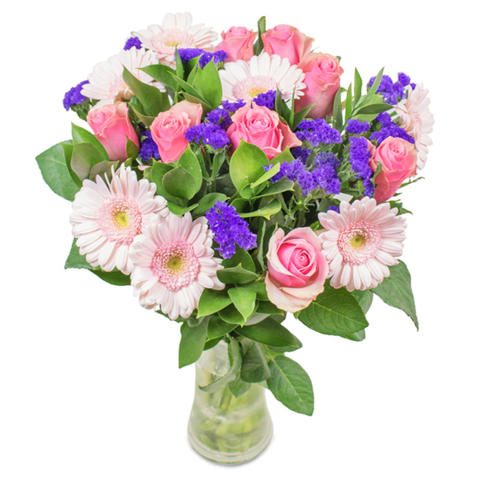 A sophisticated and fresh floral bouquet sits beautifully displayed in a clear, cylindrical vase, positioned against a pure, luminous background that highlights every nuance of colour. This Tottenham Hale arrangement features precisely seven to nine pink roses-some softly unfurling, others tightly furled-each one revealing the classic spiral at its core. Their romantic shade is expertly complemented by five to seven pale pink gerbera daisies, their round, multi-petaled heads and nearly white centers attracting the eye. Interspersed are lively clusters of bright purple statice, adding enticing texture, visual depth, and a vibrant pop of colour. The composition is unified by generous, glossy green leaves that fan around the flowers, conjuring the vitality of High Cross fields and the lushness of local canal paths. The glass vase's transparent body allows the observer to see the sturdy, water-immersed stems, reinforcing a sense of natural vitality and freshness-ideal for a doorstep delivery in the heart of Tottenham or a charming accent in a local studio. Perfect for birthdays, anniversaries, Mother's Day, or as a lasting decorative piece for a home or business in Tottenham Hale, this expertly arranged bouquet radiates sentiments of affection, joy, and celebration.